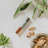 Press & Still Balance essential oil blend next to sandalwood chips, and eucalyptus and geranium leaves.