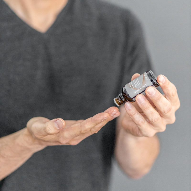 A man dispensing a few drops of Last Light Renewing Night Oil onto his fingers.