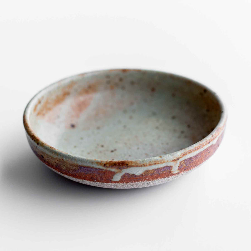 Handmade ceramic condiment dish in rust and wheat, with drips down the sides. Made by Colleen Hennessey. Approximately 4" in diameter and 1-1.5" deep.