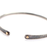 Oxidized silver open-ended bangle bracelet with flattened ends adorned by 14k gold dots.