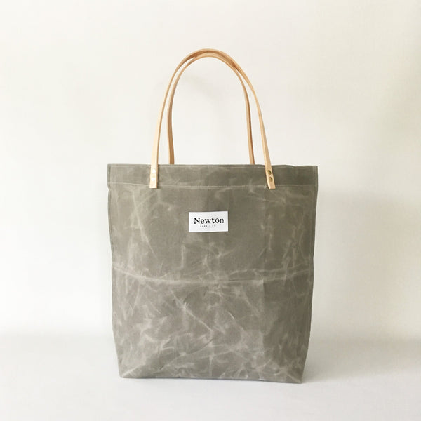 Aluminum-colored hand-waxed cotton market tote by Newton Supply. Veg-tan leather handles are attached by brass rivets.