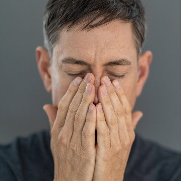 A man breathing deeply into his palms after massaging in the aromatherapy night oil. Inhaling sedative oils such as valerian root, hops and St. John's Wort help promote relaxation and deep sleep.
