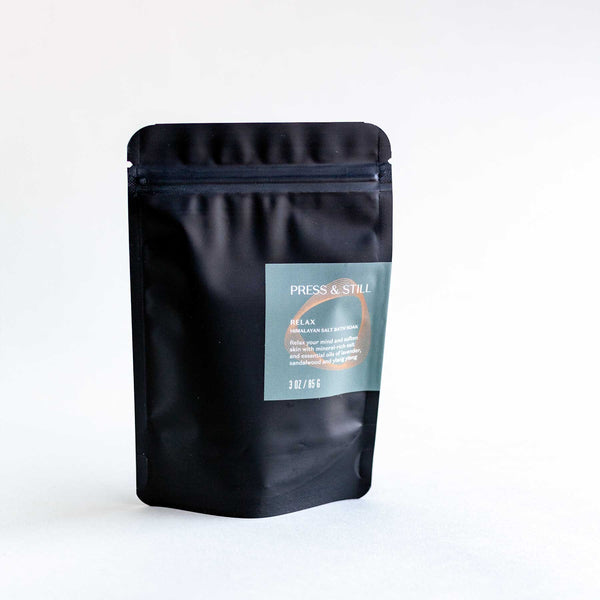 Relax bath soak made with Himalayan salt and essential oils and extracts of lavender, ylang ylang, vanilla and sandalwood. Shown in its matte black foil pouch packaging.
