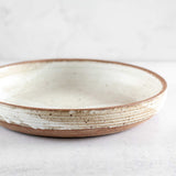 Side view of Colleen Hennessey's matte speckled ceramic serving bowl with unglazed rim.