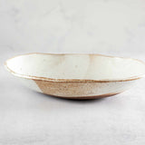 Side view of Colleen Hennessey's oval ceramic bowl in glossy speckled white.