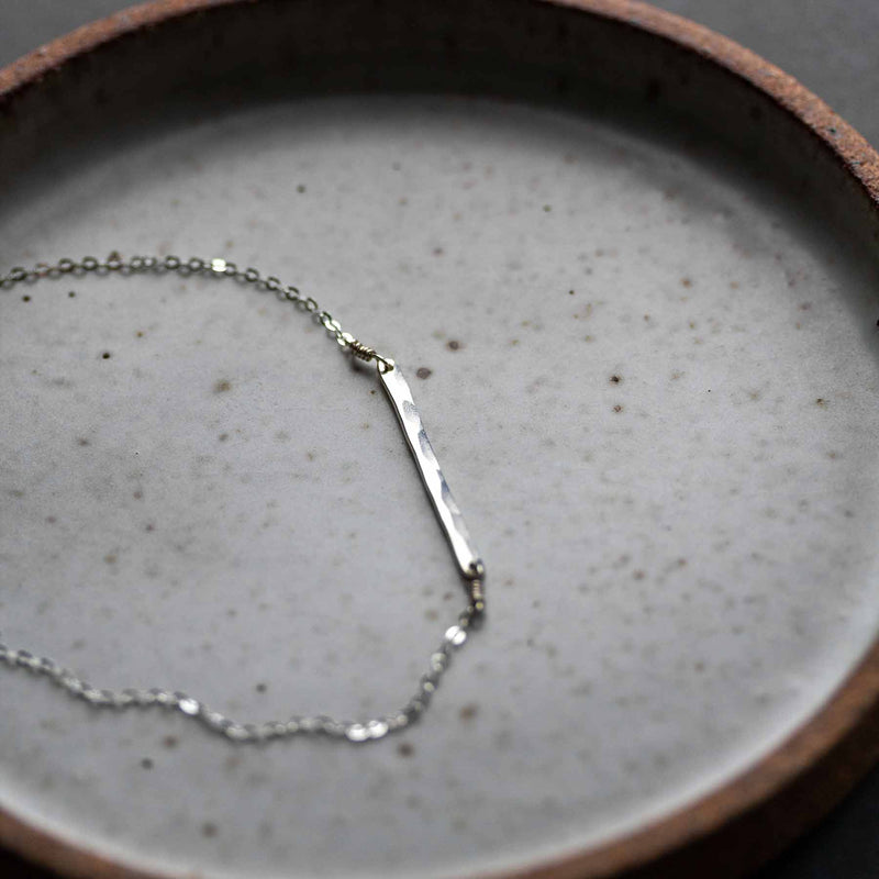 18" sterling silver Bone necklace by Desert Moon, placed on a tapas dish by Colleen Hennessey.