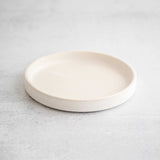 Snow white ceramic dish by Earthen against a light concrete background.