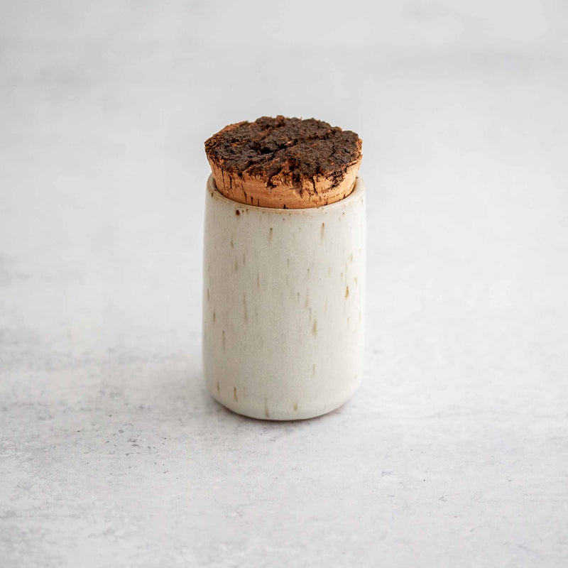 Earthen spice jar in Nest cream-colored glaze with rust flecks and raw cork bark lid.
