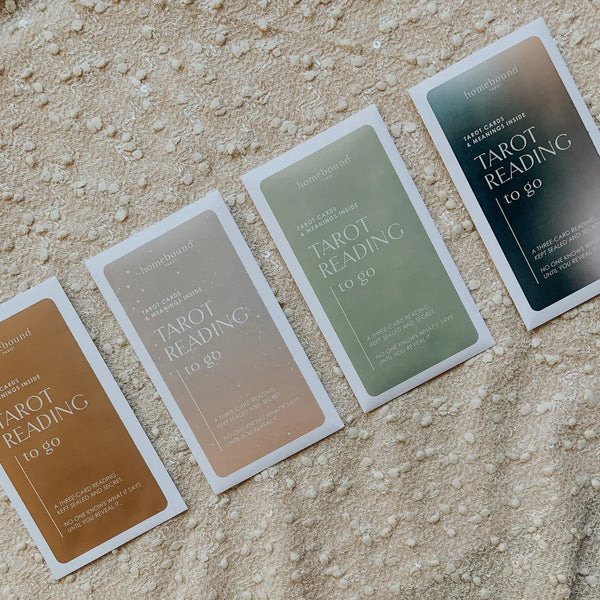 Homebound Tarot's Tarot Reading to go packs in all four colors (desert, dusk, sage and moonlight), spread on a cream-colored blanket.