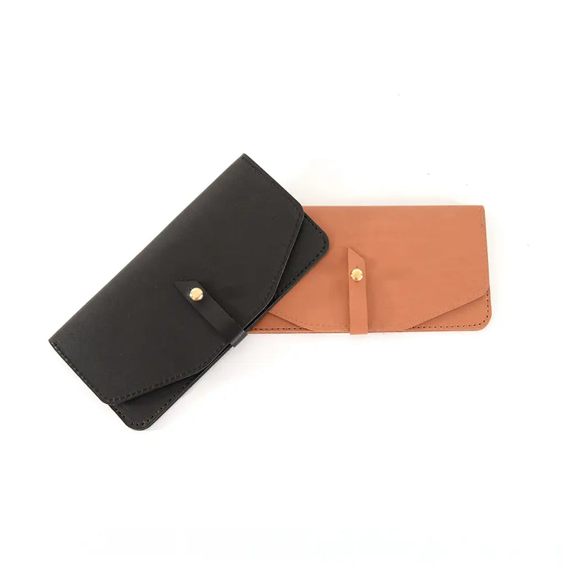 The sleek, minimal yet oh-so-functional Maxi wallet by Shana Luther. Made with vegetable-tanned leather and solid brass stud hardward. Shown here in black (left) and oak (right).