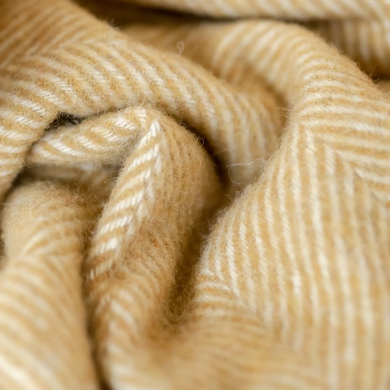 A close-up of the mustard herringbone pattern of The Tartan Blanket Co.'s recycled wool blanket.