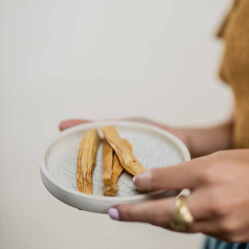 Four palo santo sticks on a crackle offering dish by Earthn.